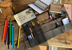 an assortment of pens, pencils, and other items on a wooden table top