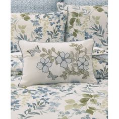 a bed with blue and green flowers on the comforter, pillows and pillow cases