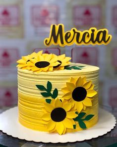 a yellow cake with sunflowers and the word mercia on top