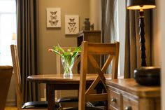 a dining room table with chairs and a vase filled with flowers sitting on top of it