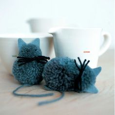 two coffee mugs sitting next to each other on top of a wooden table with yarn wrapped around them