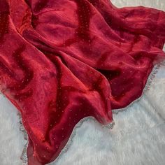 a red blanket laying on top of a white furnishing covered in beads and sequins