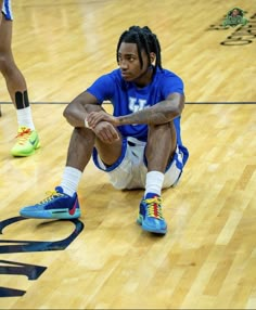 a basketball player sitting on the floor with his feet up and one foot in the air