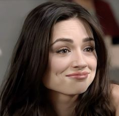 a close up of a person with long hair and brown eyes smiling at the camera