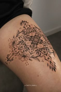 a woman's thigh with flowers and leaves tattoo on her leg, showing the back side