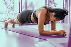 a woman doing push ups on a purple mat