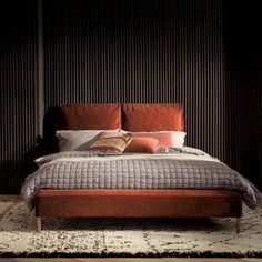 a large bed sitting on top of a wooden floor next to a wall with vertical blinds