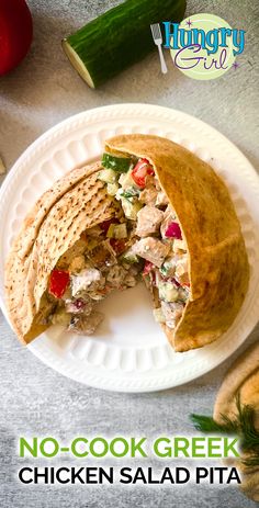 a chicken salad pita cut in half on a white plate next to cucumbers