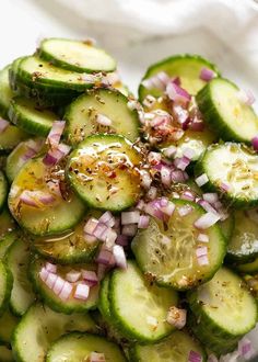 cucumber salad with onions and herbs in a glass bowl on a white surface