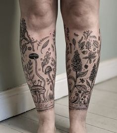 a person with tattoos on their legs standing in front of a wall