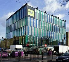 a large glass building sitting on the side of a road next to a parking lot