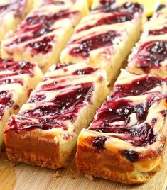 several slices of cheesecake with raspberry toppings on a wooden cutting board