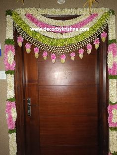 the door is decorated with flowers and garlands for an entrance to a wedding reception