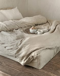 an unmade bed sitting on top of a wooden floor