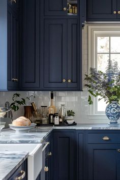 a kitchen with blue cabinets and marble counter tops, along with a vase filled with flowers