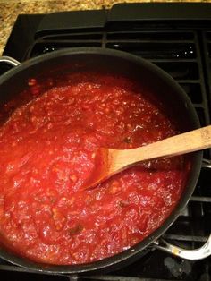 a wooden spoon is in a pot of sauce on the stove top, ready to be cooked