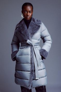 Designed For Utmost Warmth, This Mid-Length Coat Is Crafted From Heat Sealing Puffer Fabric, Making It The Ultimate Trend-Forward Yet Protective Layer. Featuring A Waist Tie Belt That Adds Form To The Silhouette, While A Soft Faux Fur Notched Collar And Cuffed Sleeves Adds Luxury Detailing. Sumptuous Quilted Detail Allows For A Sleek And Seamless Fit.Mid-Lengthlong Sleevestie Beltfur Detailing Puffer Coats, Ladies Clothes Fashion, Gray Design, Shop Mens Clothing, Suit Shop, Airport Outfit, Notched Collar, Karen Millen, Women's Coats & Jackets