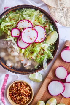 a bowl filled with lettuce and radishes next to some sliced onions