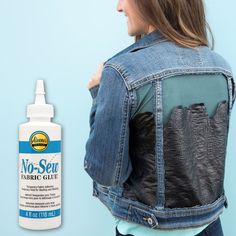 a woman wearing a jean jacket with patches on it and a bottle of fabric glue