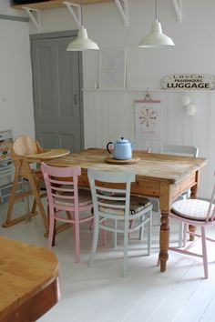 a wooden table and chairs in a room with white walls, wood floors and light fixtures