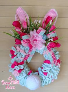 a pink and blue wreath with flowers on the front is hung on a wall next to a white ball