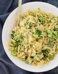 a white bowl filled with rice and broccoli on top of a blue cloth