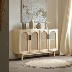 a wooden cabinet with two vases on top and a rug in front of it