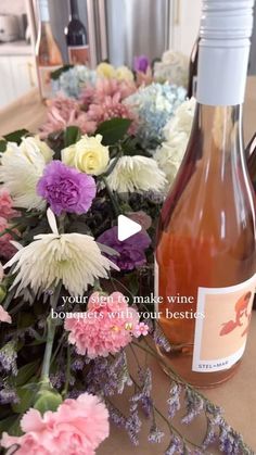 a bottle of wine sitting on top of a table filled with flowers and greenery