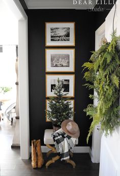 a room with black walls and pictures on the wall next to a chair in front of a christmas tree