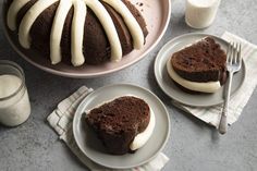 two plates with slices of cake on them next to a glass of milk and fork