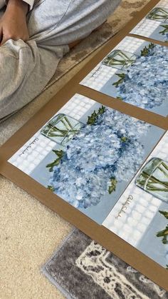 a person sitting on the floor with their feet up next to some pictures that have flowers in them