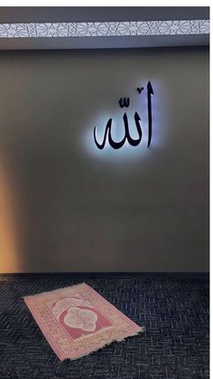 an illuminated sign in the middle of a room with a rug on the floor next to it