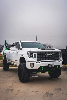 a white truck parked in a parking lot next to a green and white flag pole