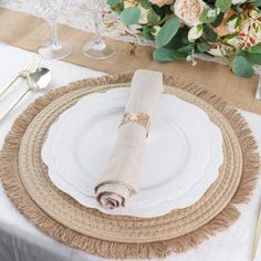 a place setting with white plates and silverware on a linen tablecloth, surrounded by flowers