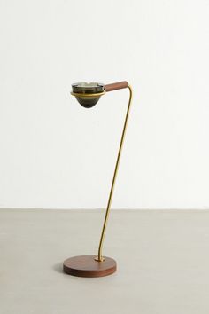 a metal and wood table lamp on a wooden base with a white wall in the background