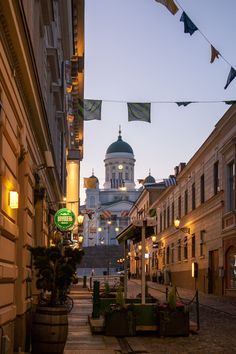 a city street with buildings and flags hanging from it's sides at night time