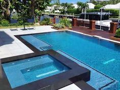 an empty swimming pool in the middle of a backyard with trees and shrubs around it