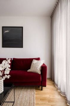 a living room with a red couch and white curtains