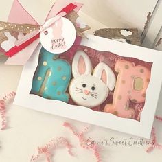 three decorated cookies in a box with a bow on the top and some bunny ears