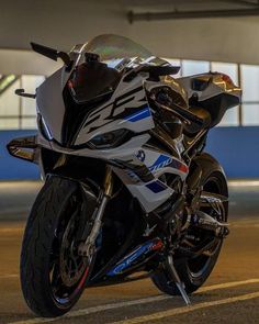 a white and blue motorcycle parked in front of a parking garage area with lights on