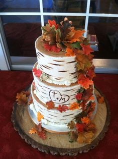 a wedding cake with fall leaves on it and the words love is in the middle