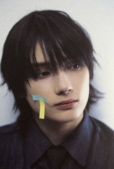 a young man wearing a black shirt and tie with yellow tape on his face, looking at the camera