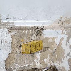 a yellow box sitting on the side of a wall next to a pile of rubble