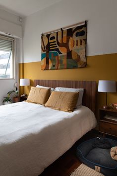 a large bed sitting in a bedroom next to a painting on the wall above it