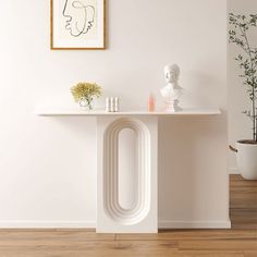 a white table with vases and flowers on it in front of a framed art piece