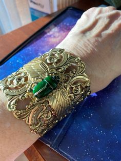 "Egyptian scarab green scarab cuff Wide cuff 2-1/2 inches, scroll pierced antique gold plating over brass.  Open in back for ease of wearing. Winged layered scarab wings with large resin and crystal detailed dark emerald green scarab. Adjustable size 7,8,9 Rich vintage patina Lucky beetle. Speaks life. This is a show stopper. Gorgeous! Limited edition. \"Angelina Verbuni Designs\" Made in USA MyElegantThings" Antique Gold Cuff Jewelry, Elegant Green Metal Cuff Bracelet, Handmade Green Cuff Bracelet For Formal Occasions, Arcane Jewelry, Gold And Emerald Jewelry, Scarab Wings, Egyptian Design Pattern, Emerald Green Jewelry, Dark Beauty Fashion