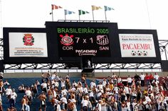 a large group of people standing in front of a scoreboard at a soccer game