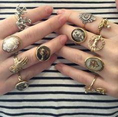 a woman is holding her hands together with many rings on them, including an angel