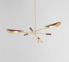 a brass chandelier with five lights hanging from it's sides and three wooden spoons on each end