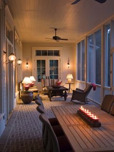 a long table with candles on it sitting in front of some chairs and windows next to a door